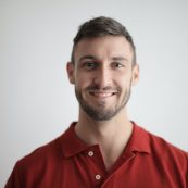 a man in a red shirt smiling at the camera.