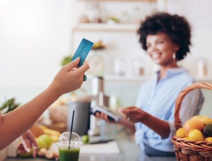 a woman holding a credit card in a kitchen.